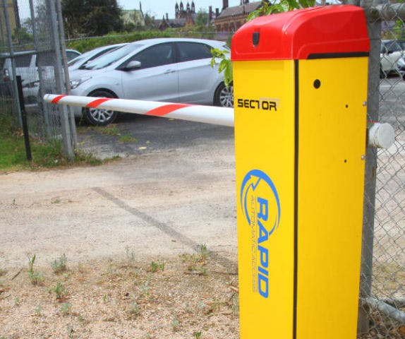Close-up of a sector boom gate motor cabinet at the entry of a car park.