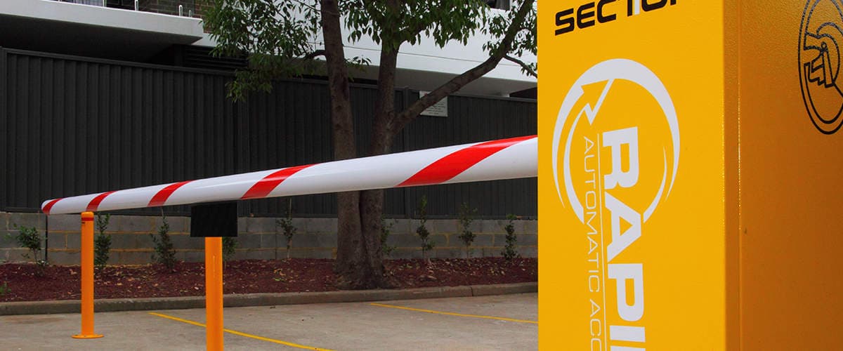 Close-up of a boom gate cabinet and arm at the entry of a car park.