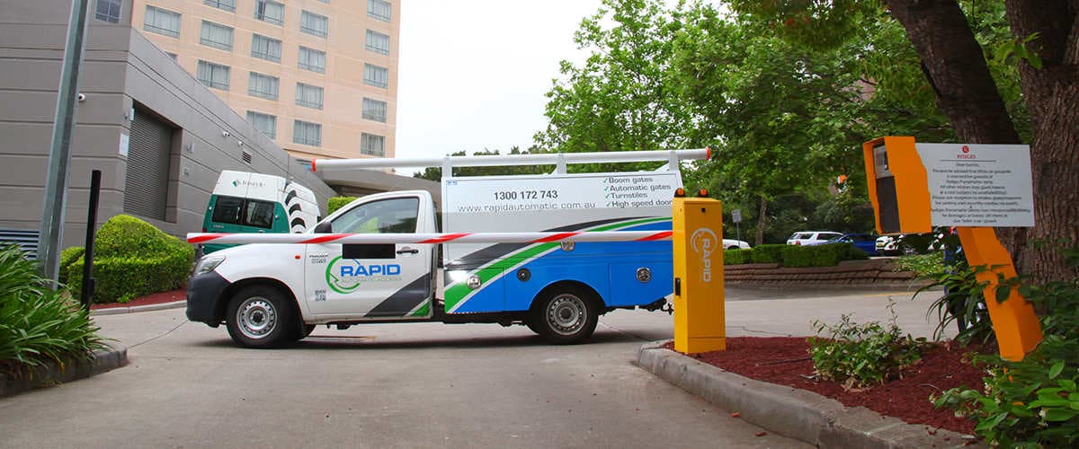 A boom gate with a Rapid Automatic service vehicle parked behind it.