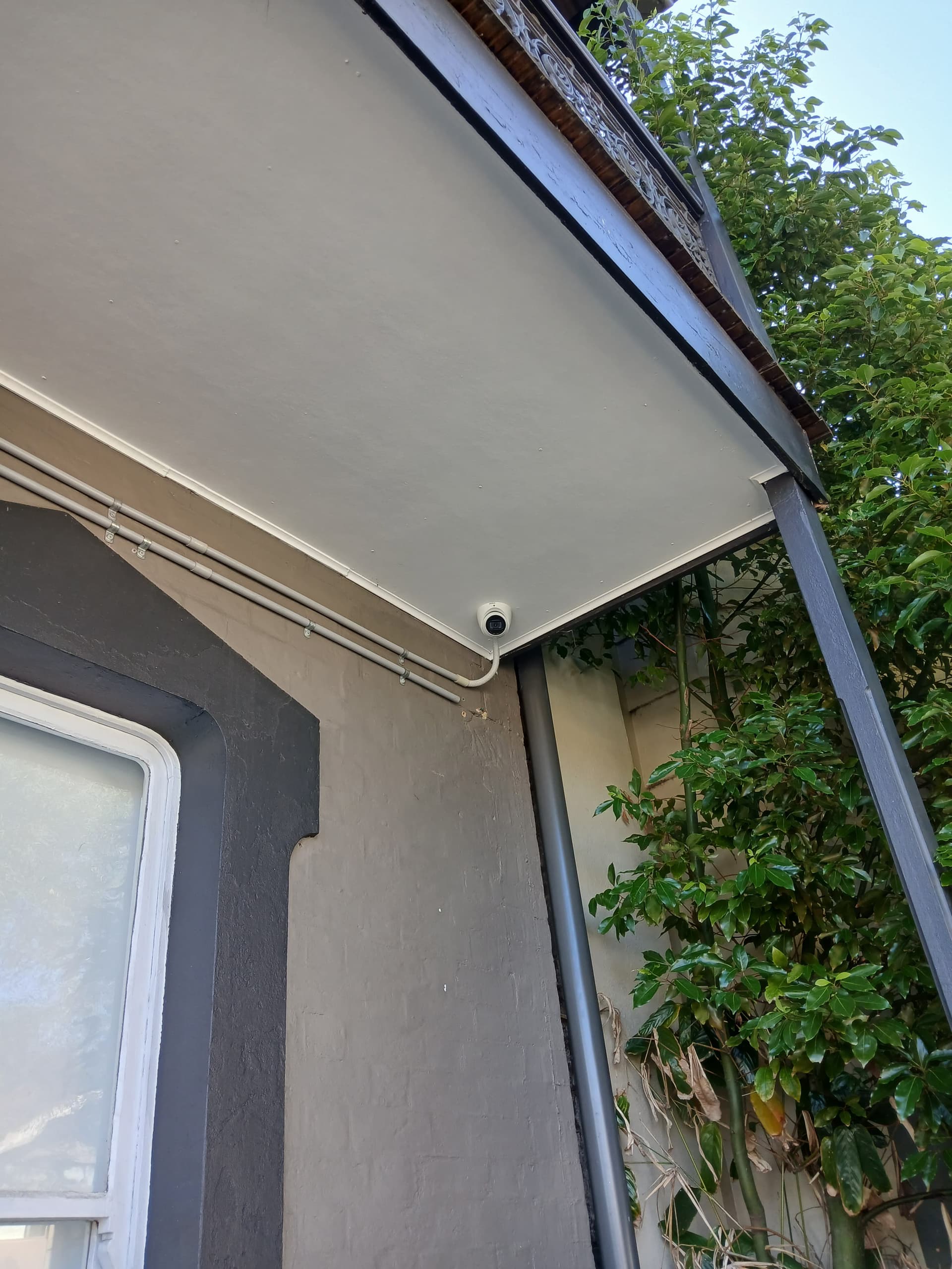 Outdoor security camera mounted under an eave.