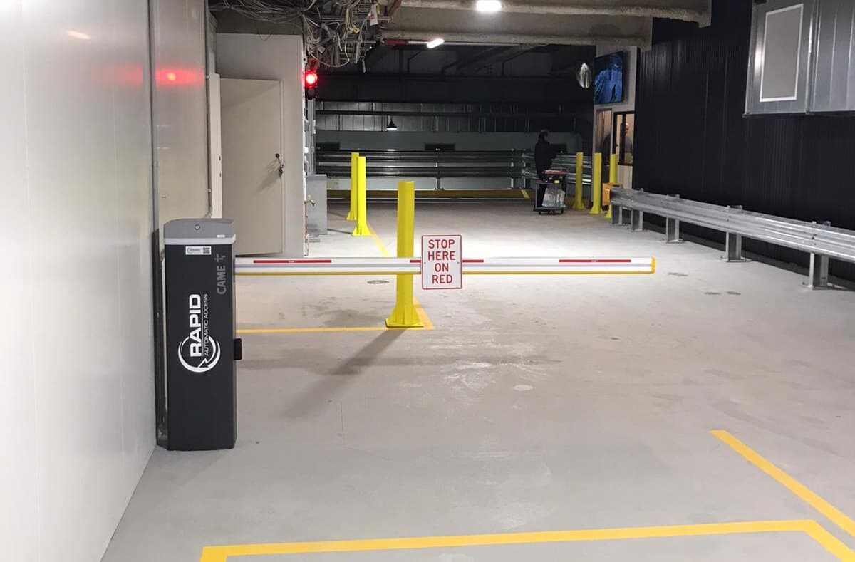 Yellow parking bollards installed beside a controlled car park entry.