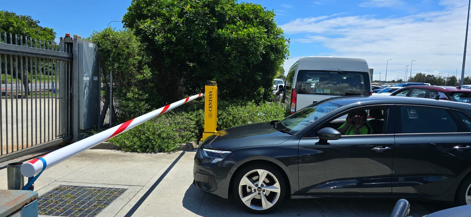Vehicle passing a raised boom gate at a busy commercial car park