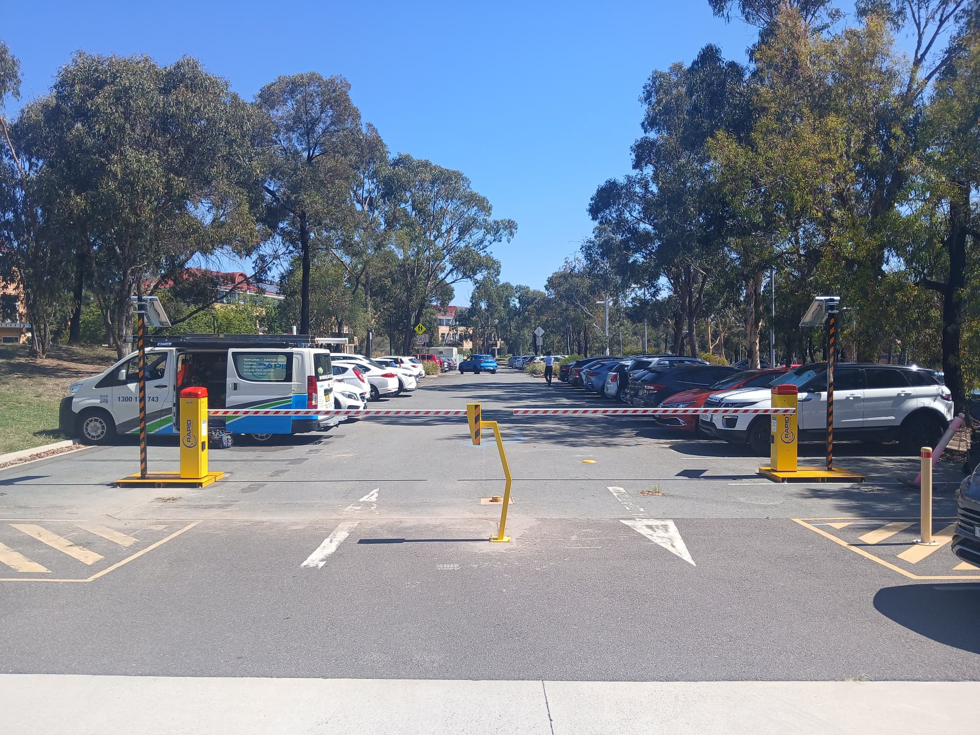 Separate boom-gate entry and exit lanes across an outdoor car park