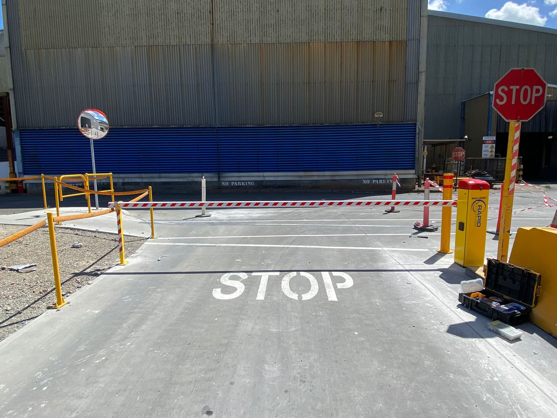 Closed boom gate beside a marked stop line at an industrial vehicle entrance