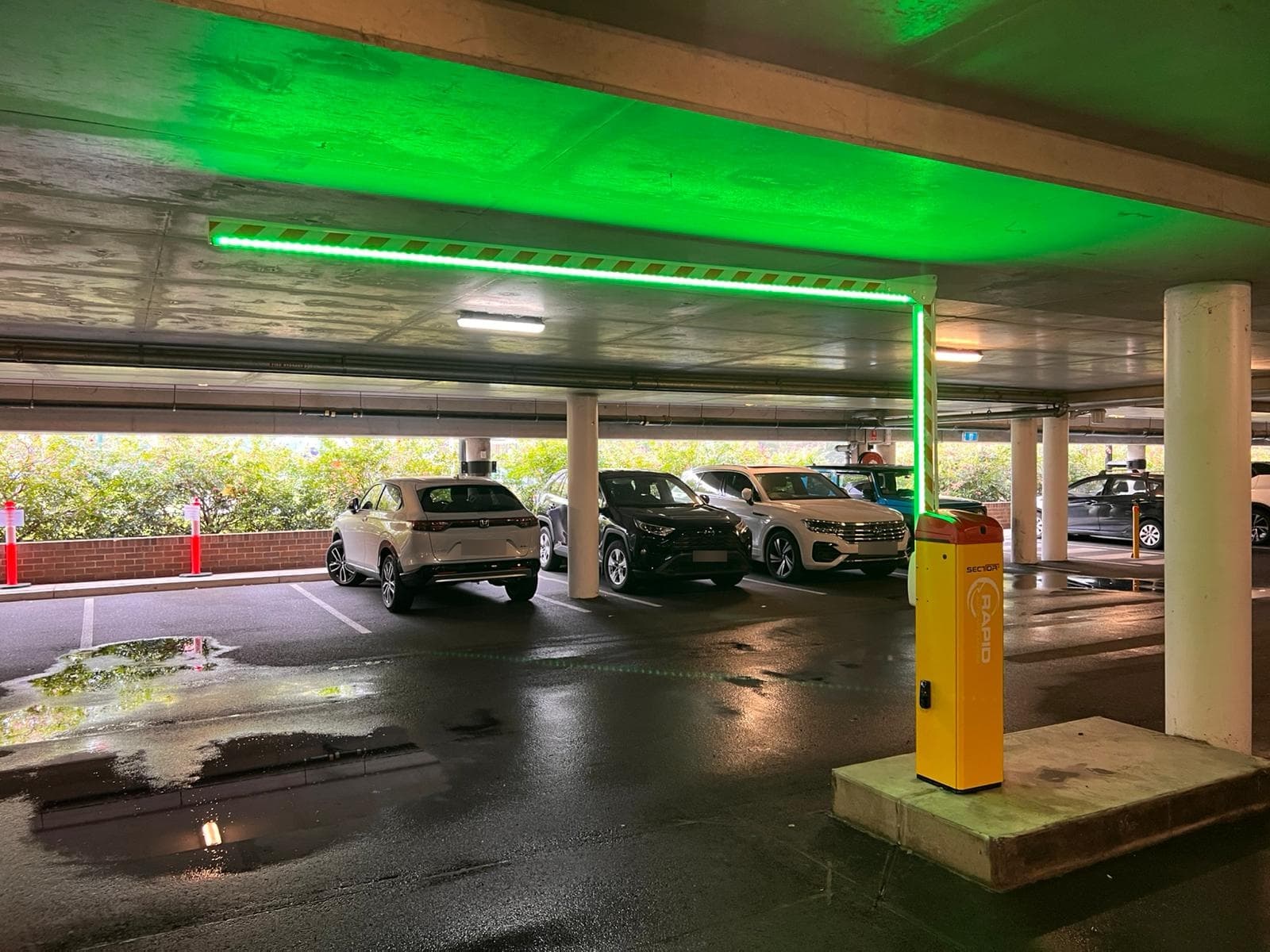 Rapid boom gate with green illuminated arm inside a covered car park