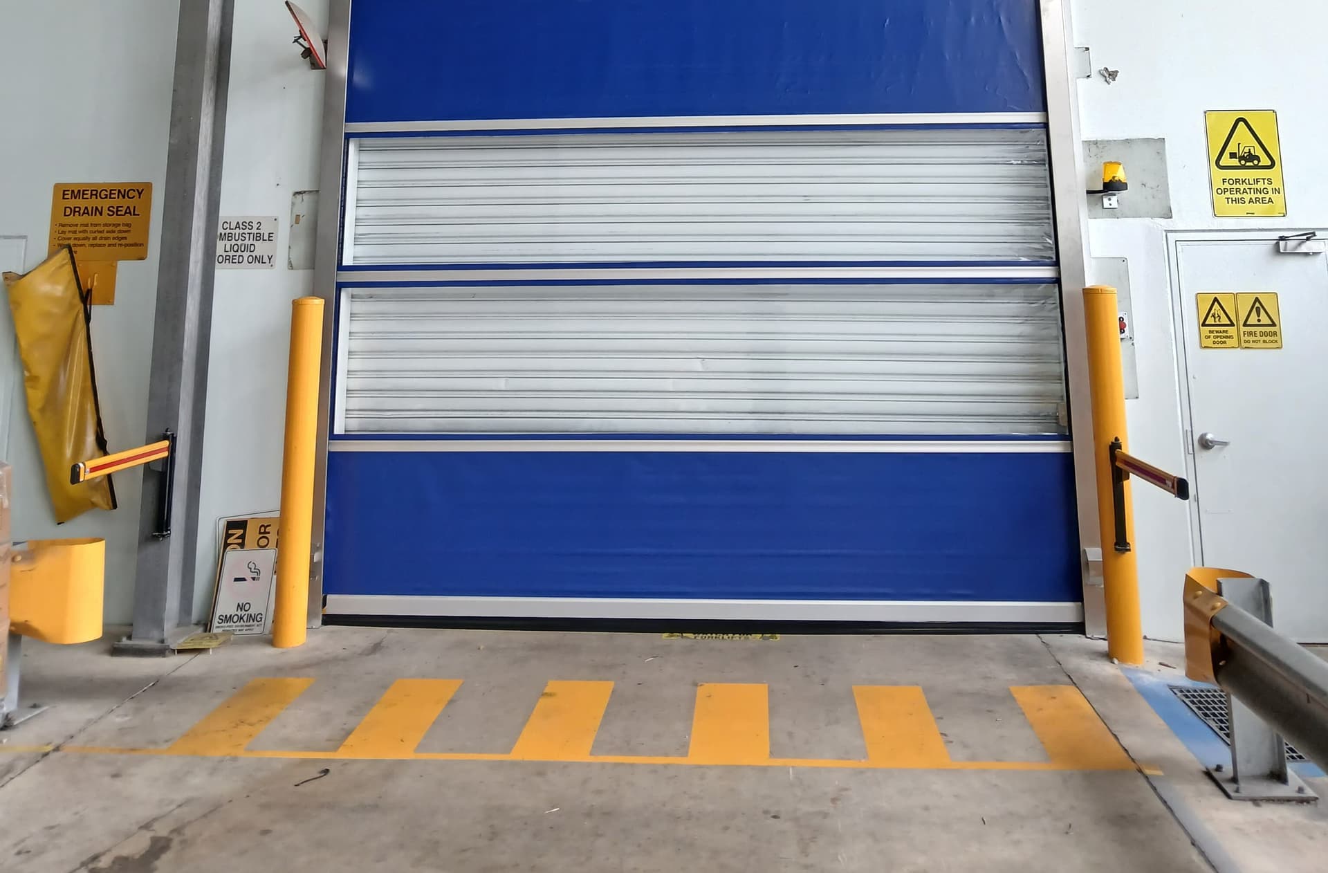 Fixed yellow safety bollards protecting an industrial doorway.