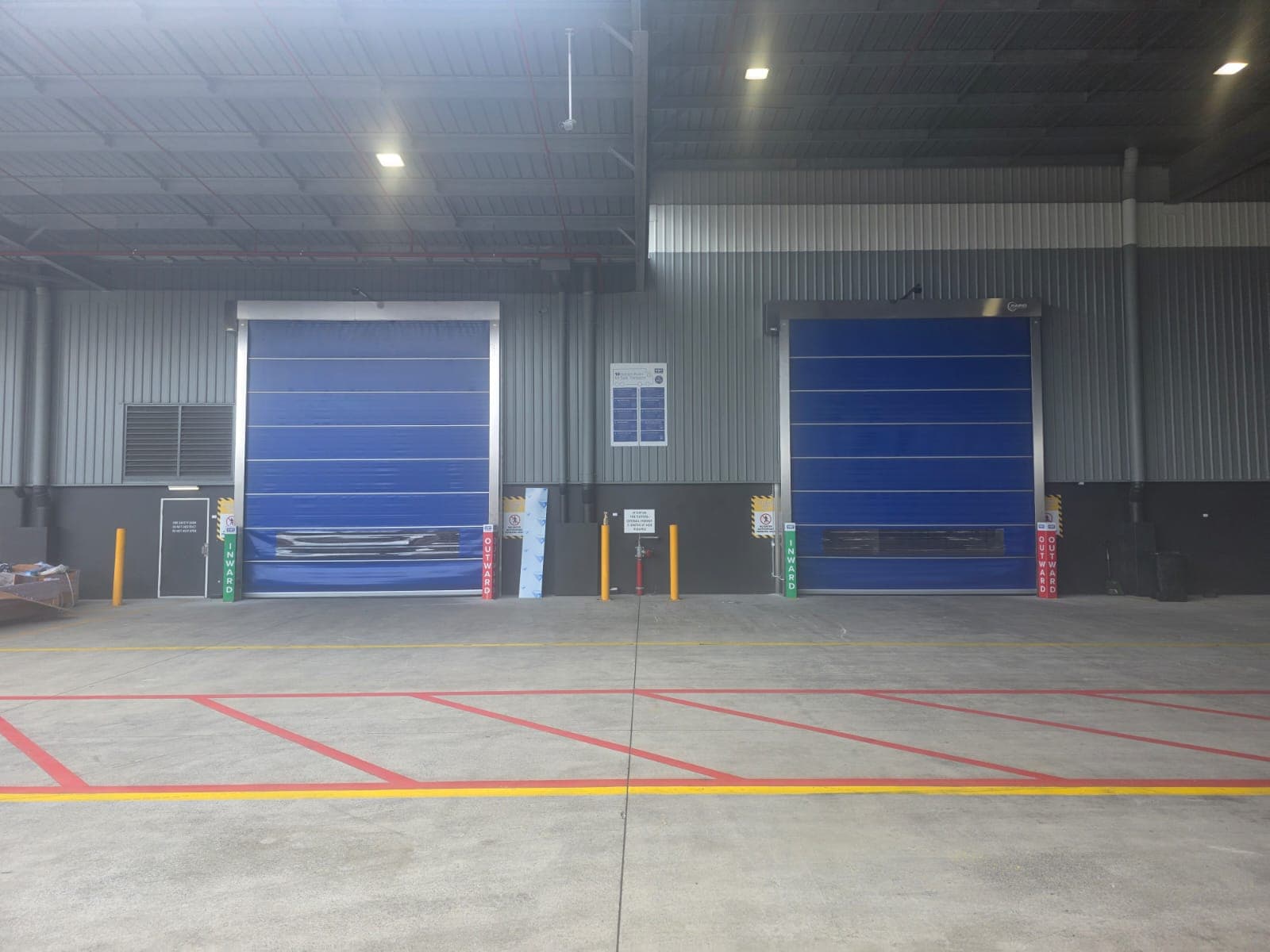 Two blue high-speed doors installed across marked traffic lanes inside a warehouse