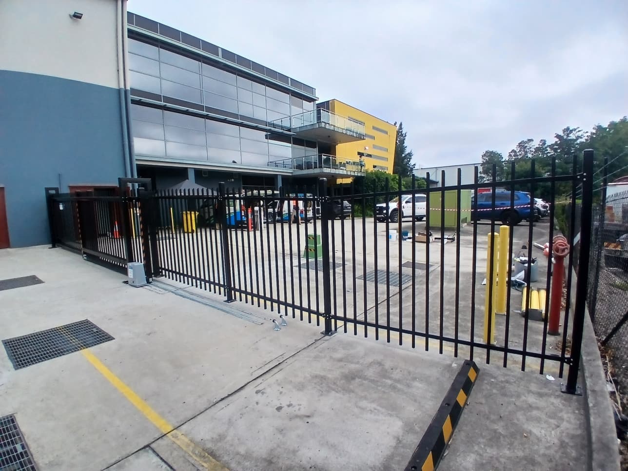 Black sliding gate running along an industrial building boundary