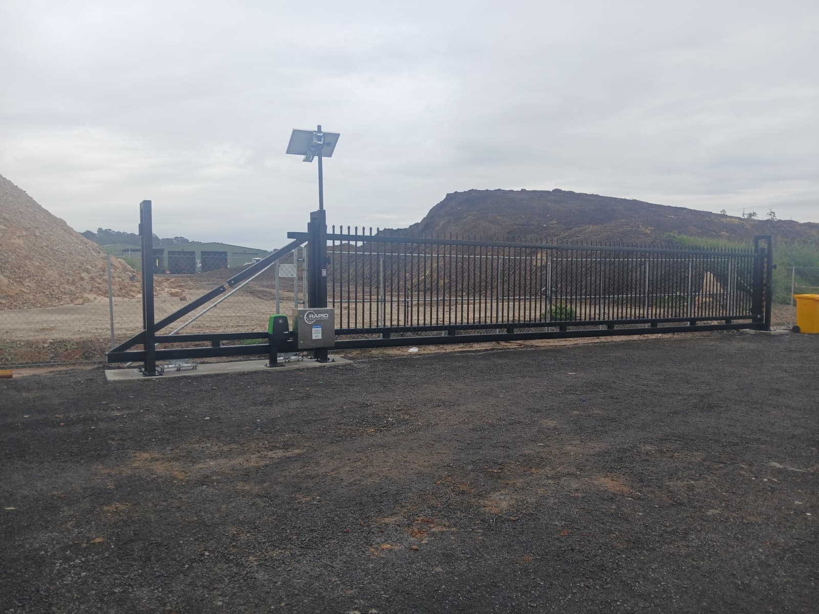 Completed black sliding gate across an industrial vehicle entrance.
