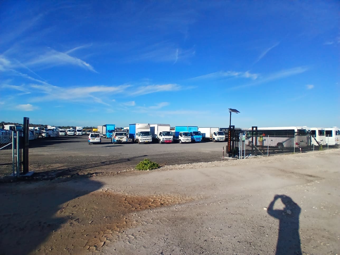 Open black sliding gate at a wide commercial vehicle yard
