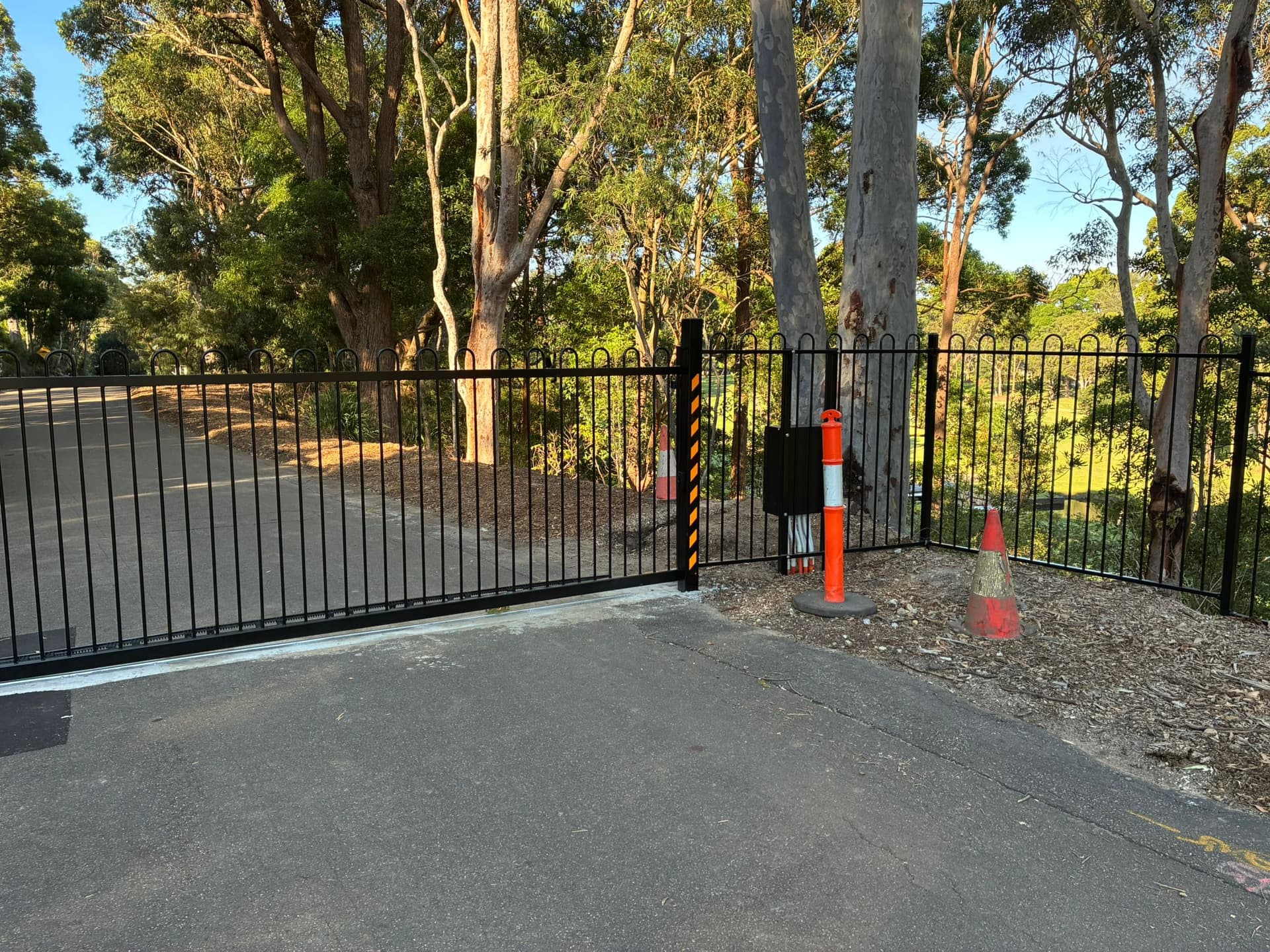 Black sliding gate with hazard-striped posts at a controlled driveway
