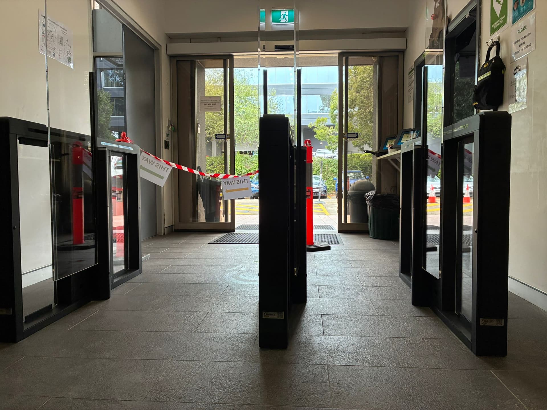Black speed-gate lanes with glass barriers across an office lobby