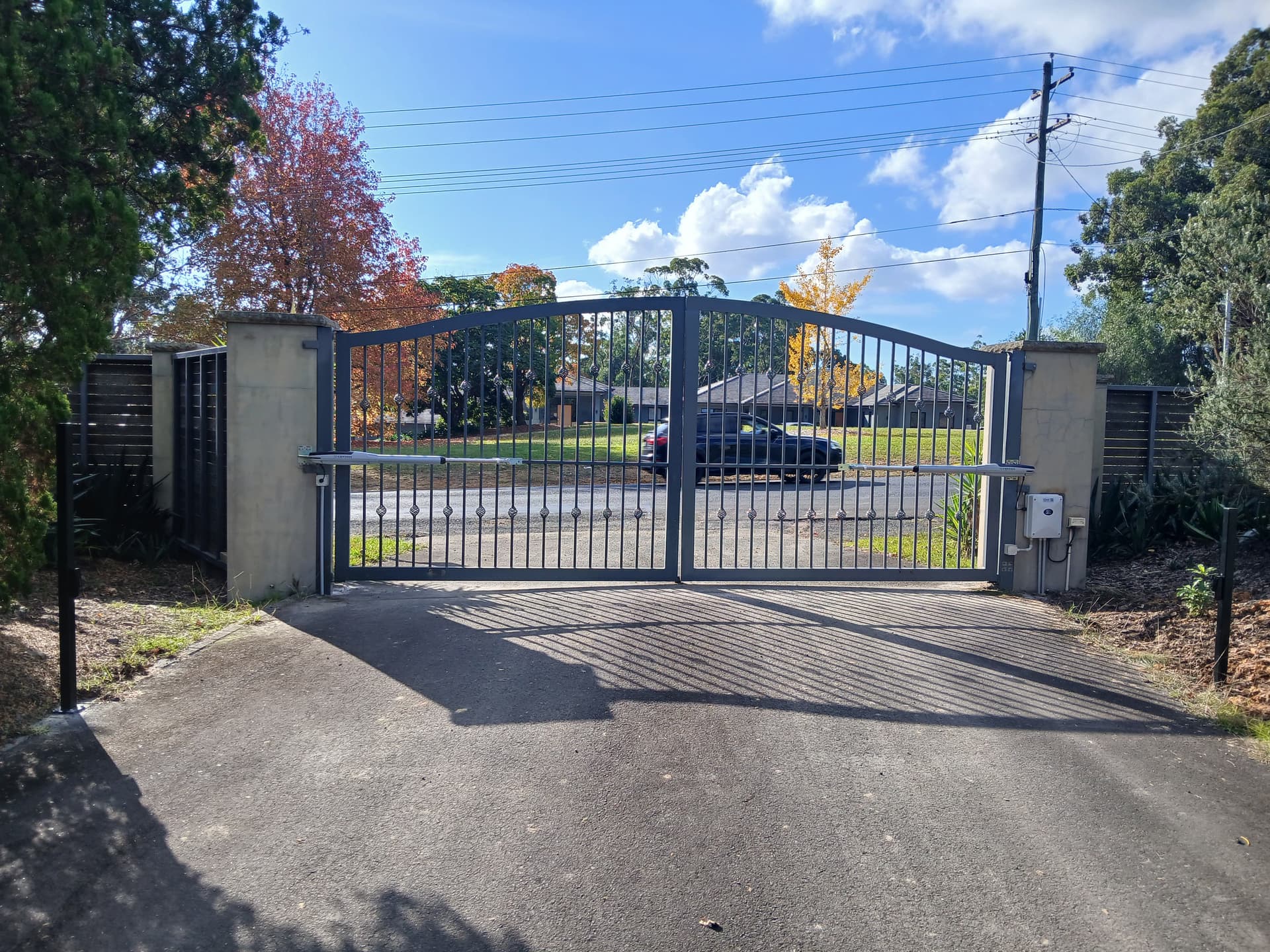 Blue-grey ornamental double gates at a landscaped residential property entrance
