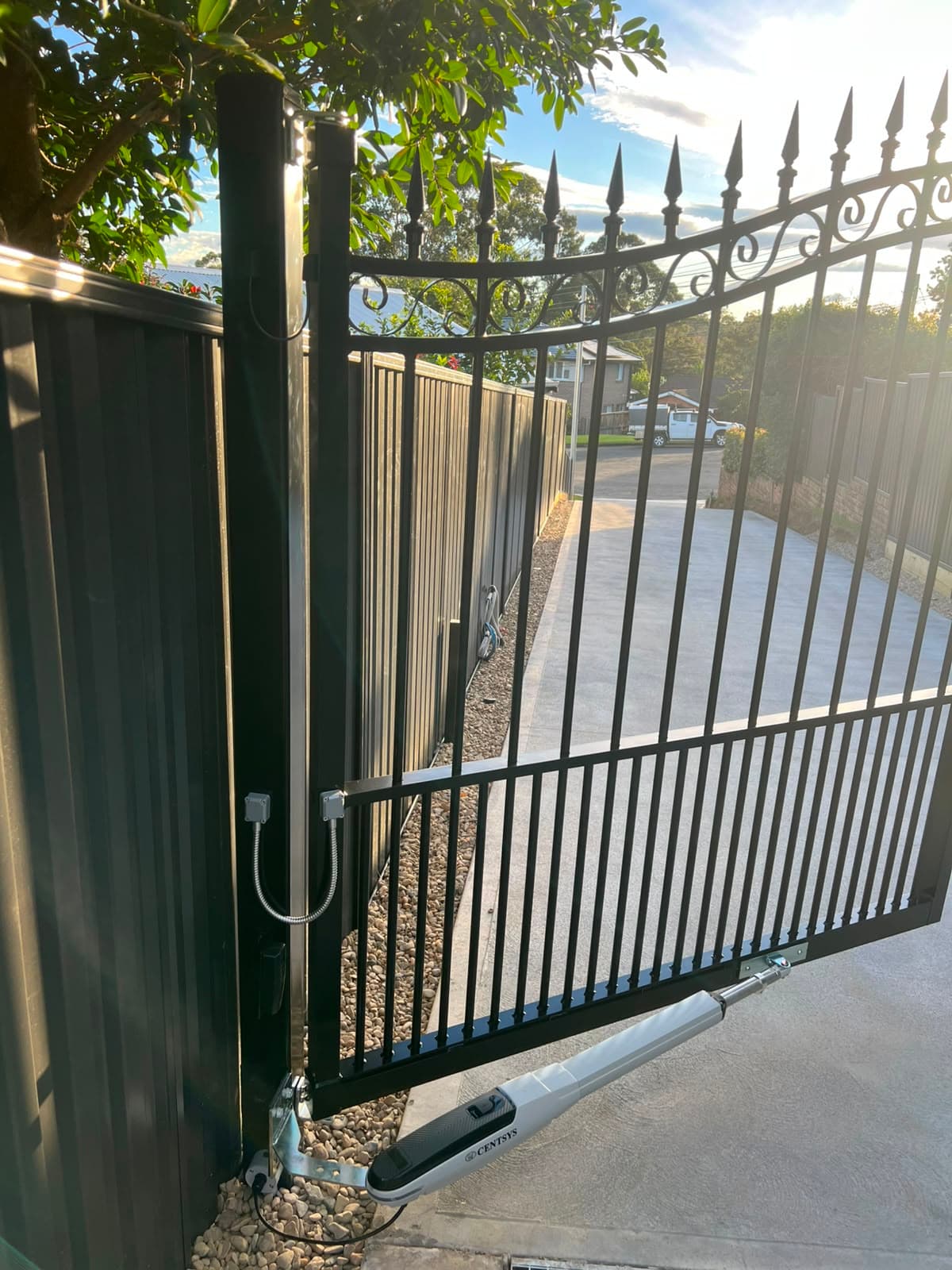 Linear actuator mounted behind an ornamental black swing gate