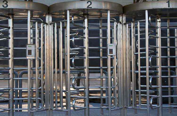 A row of three turnstiles at the entry to a train station.