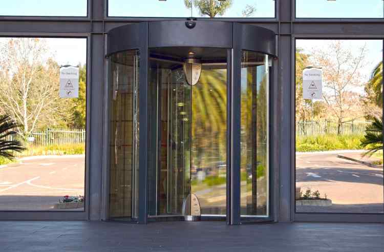 A large black automatic revolving door serving as the entry point to a large retail shopping complex.