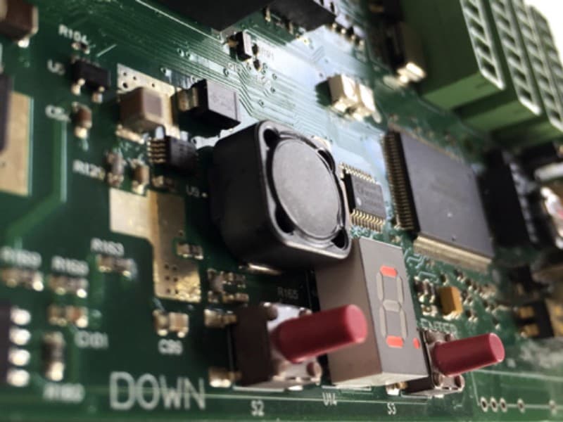 Close-up of an electronic control board for an automatic door system, featuring a digital display, microcontroller components, push buttons, and connection terminals.