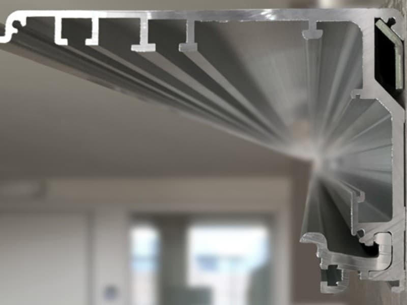 Cross-sectional view of an aluminium profile for an automatic sliding door system, showing multiple guide channels and mounting grooves for door components.