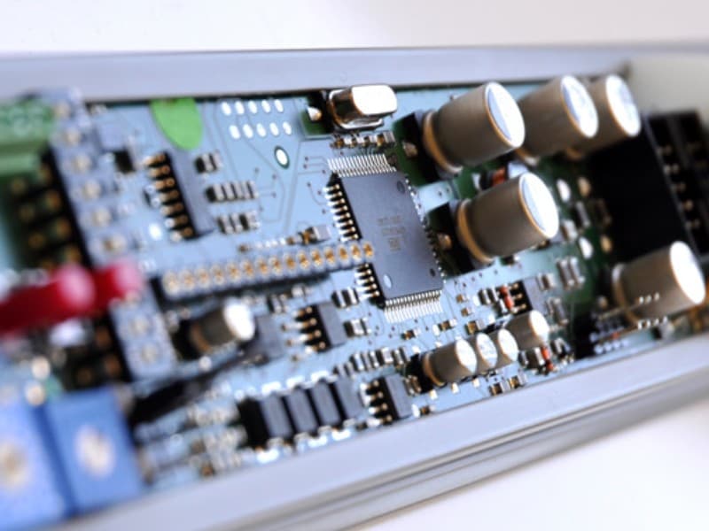 Macro shot of an electronic circuit board inside an automatic door system, showing capacitors, microchips, and surface-mounted components for motor control and automation.