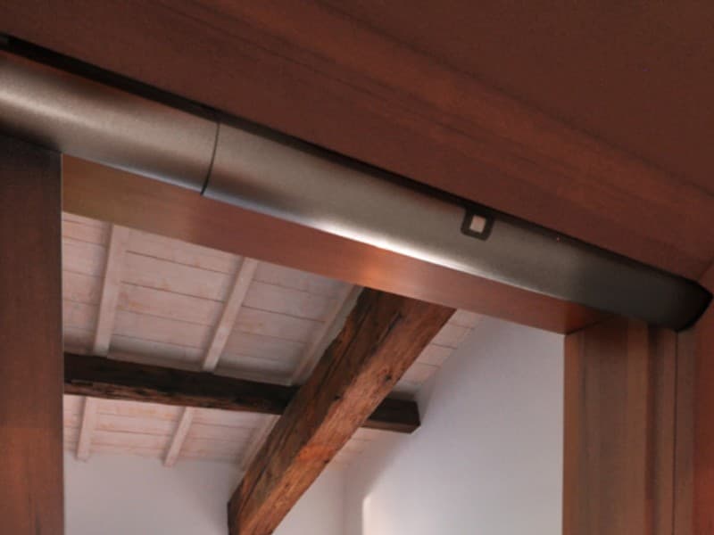 Close-up of an automatic swing door actuator installed in a timber doorway, blending with exposed beams and a rustic ceiling in a modern interior.