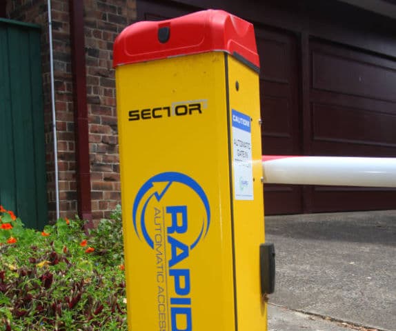 Close-up of a sector boom gate motor cabinet at the entry of a car park.