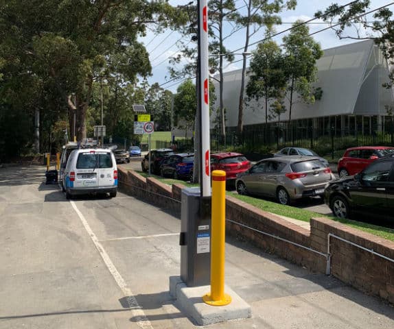 Side view of a high-traffic volume boom gate with a token and payment system for a hotel car park.