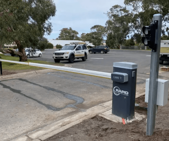 Close-up of a high-volume boom gate motor cabinet and integrated traffic management system at the entry of a car park.