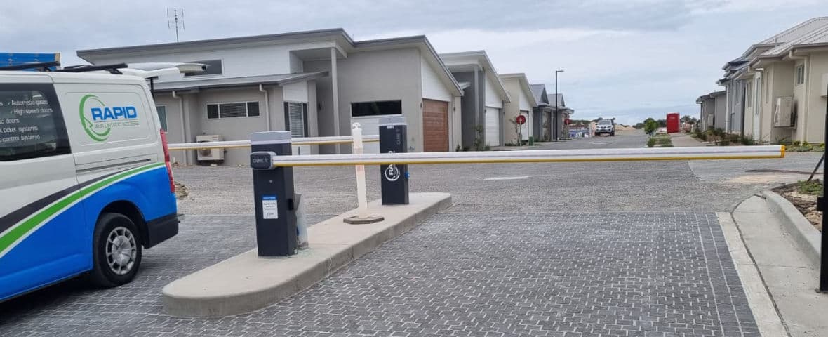A Rapid Automatic technician's vehicle parked behind double adjoining boom gates at the joint entry/exit of a retirement village.