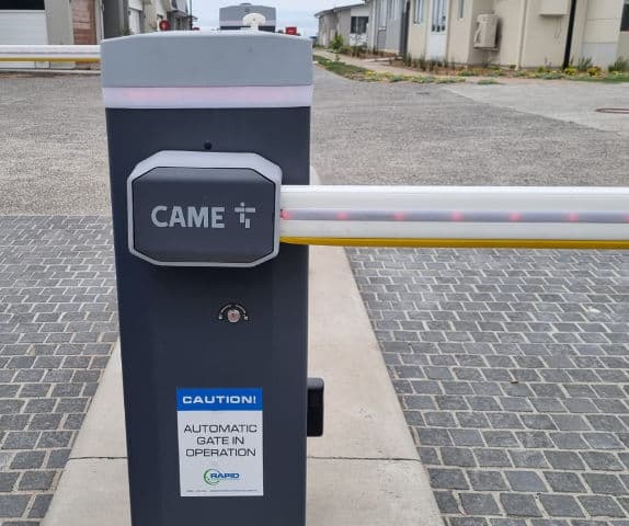 Close-up of a boom gate motor cabinet and arm at the entry of a retirement village.