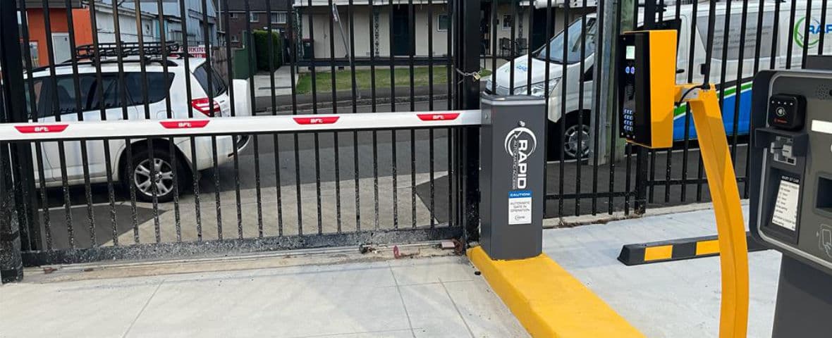 Close-up of a boom gate arm and wireless intercom and payment system.