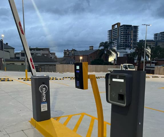 Close-up of a boom gate arm and wireless intercom and payment system.