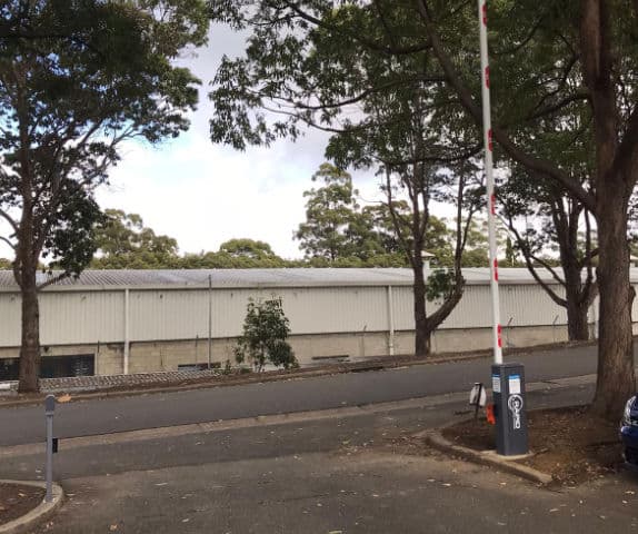 Close-up of a boom gate arm completely open at the entry of a staff car park.