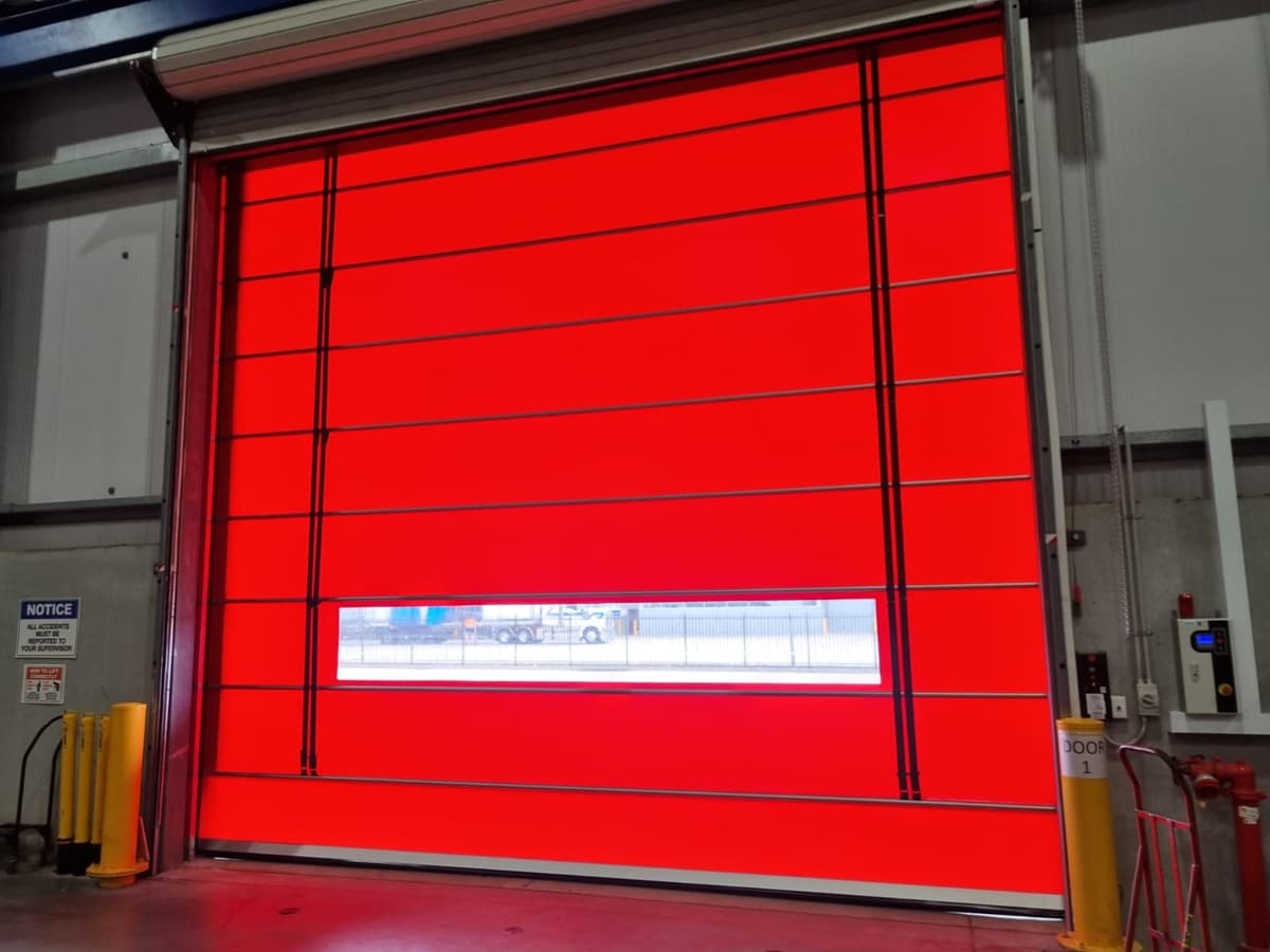 Warehouse high-speed door with safety bollards, shot from inside.