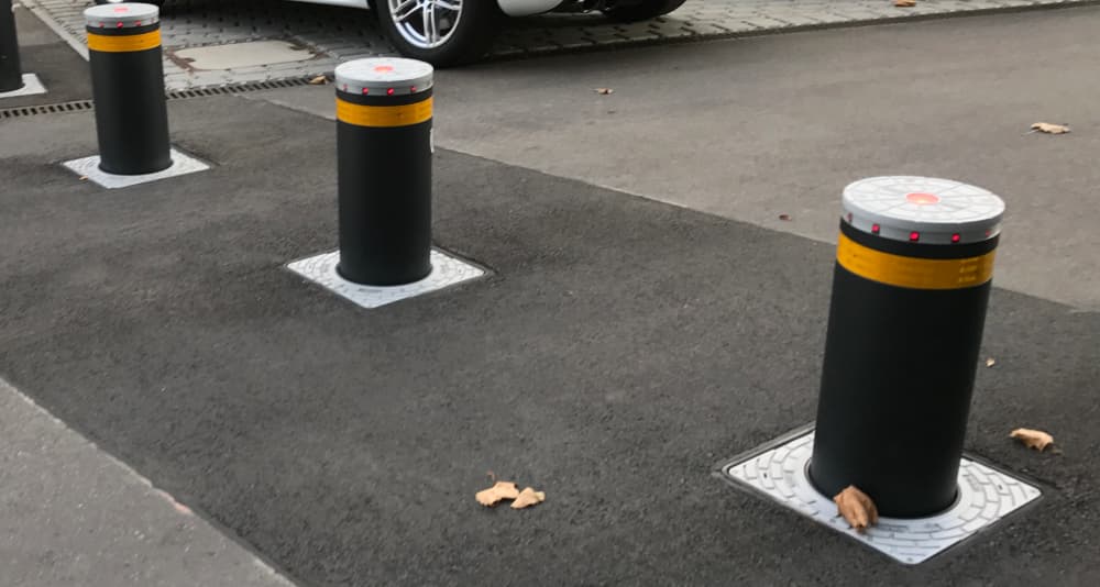 Automatic retractable bollards raised in a roadway access area.
