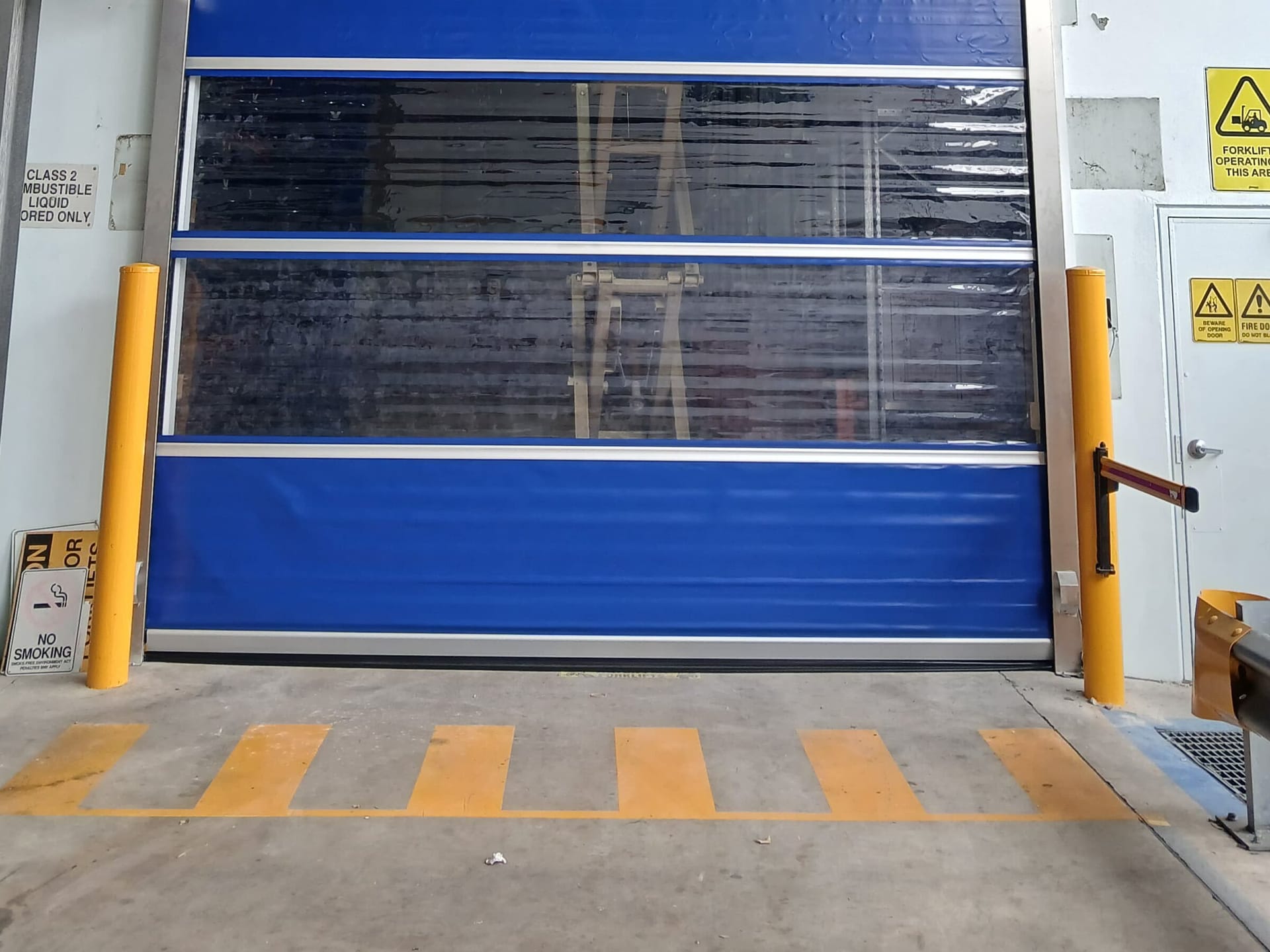 Yellow safety bollards protecting an industrial doorway and pedestrian access area.
