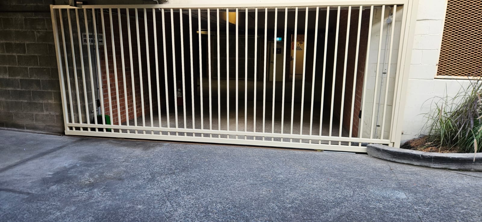 Cream indoor sliding security gate closed across a controlled car park entrance.