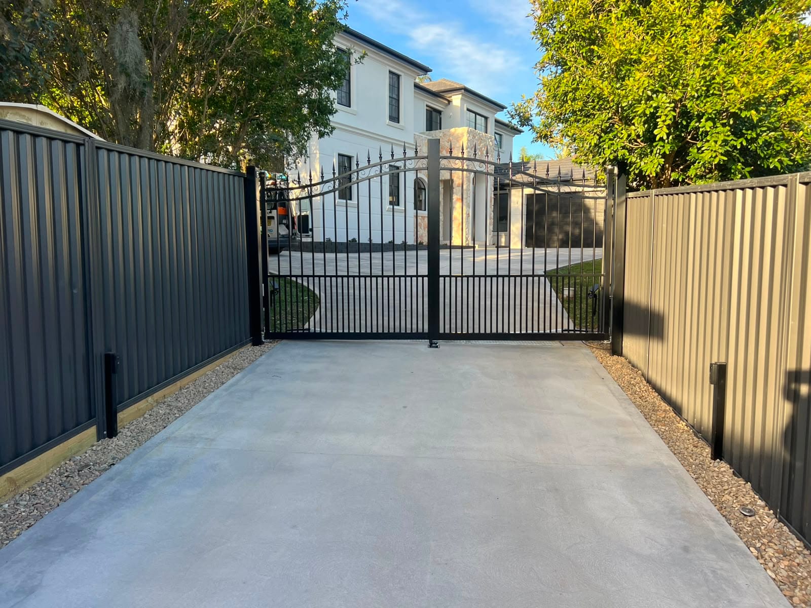 Completed black automatic swing gates across a residential driveway.