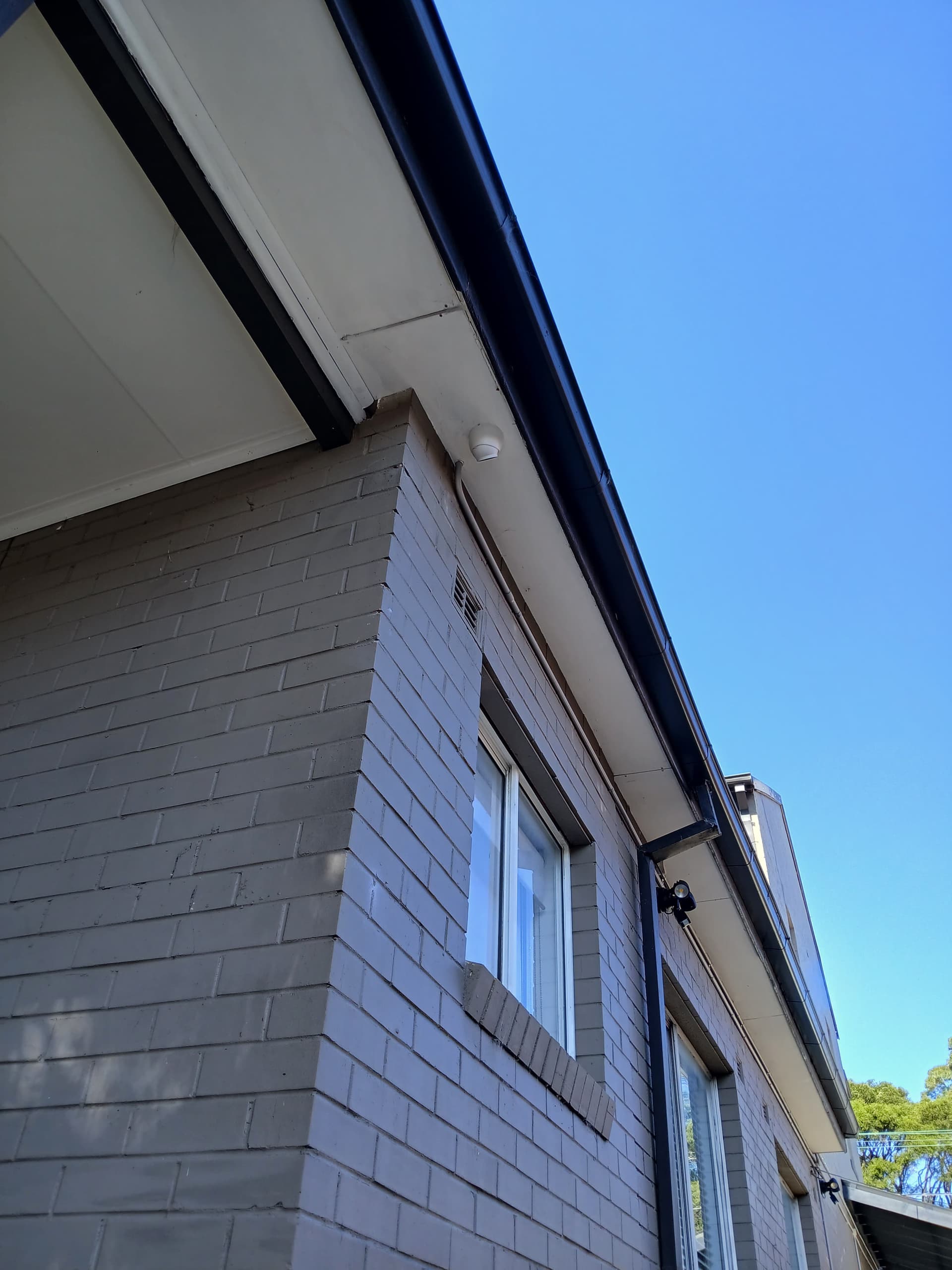 Security camera mounted on the corner of a brick building.