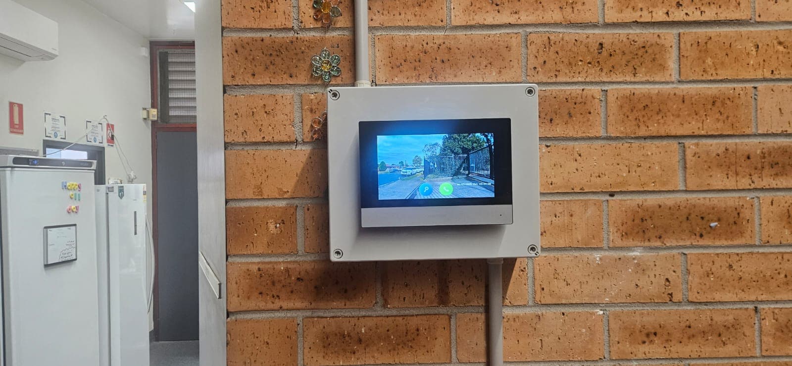 Access control touchscreen panel mounted on a brick wall.