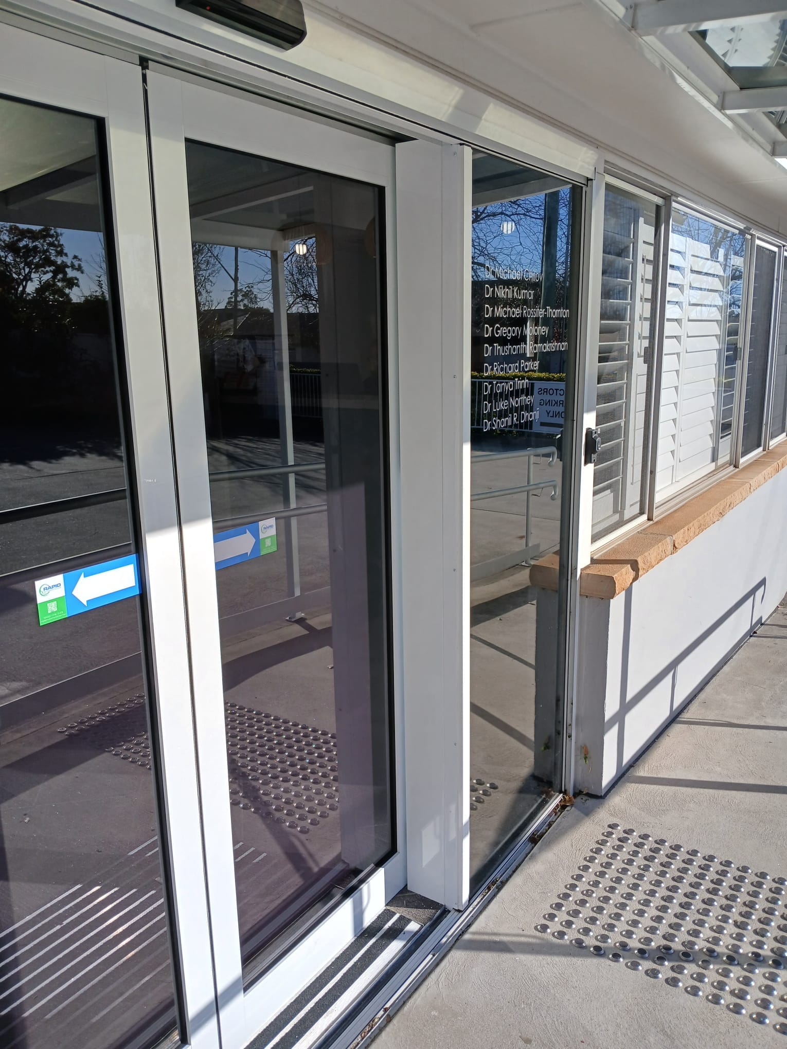 Accessible automatic sliding door entry with ramp and tactile indicators.