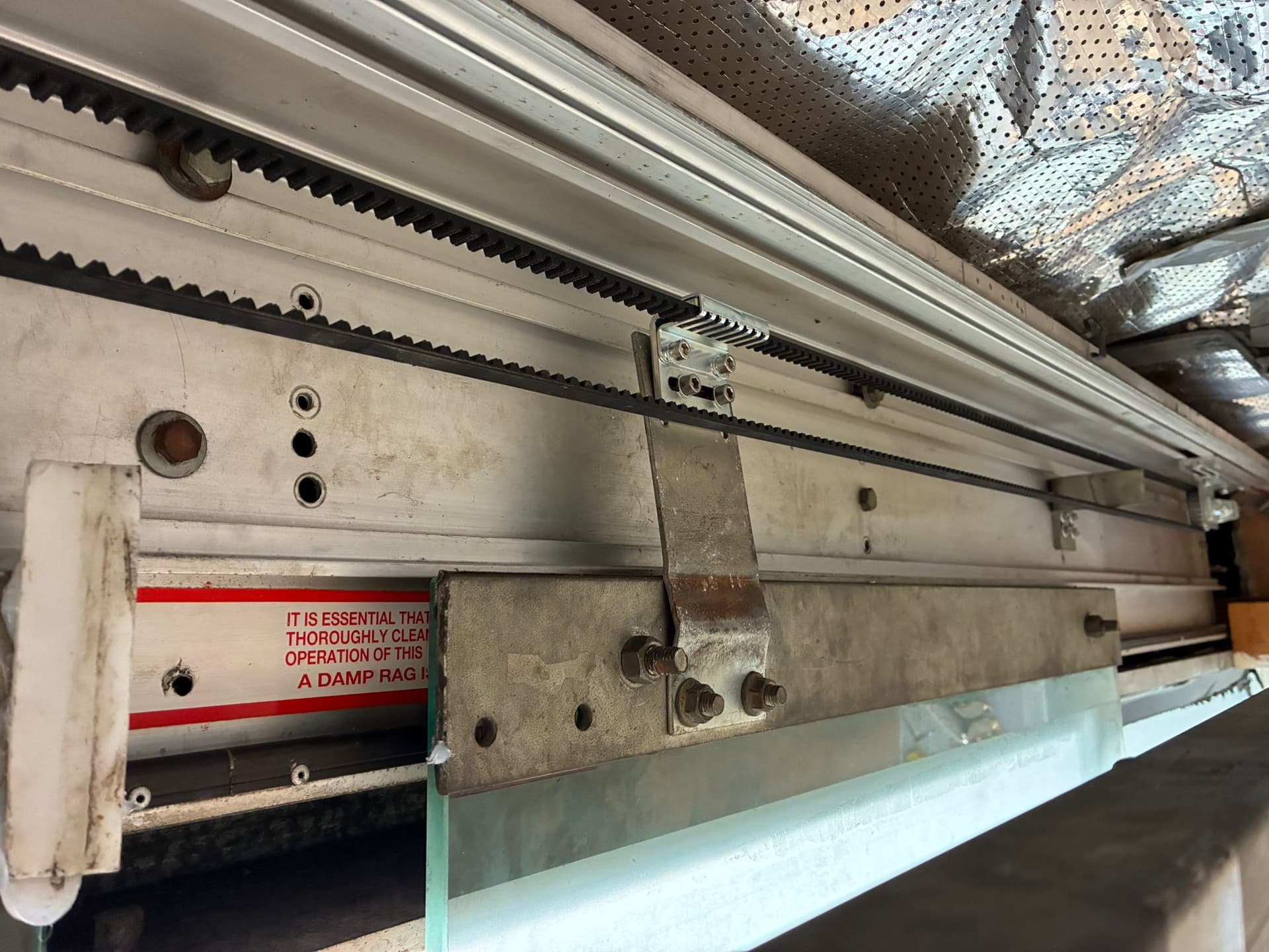 Toothed drive belt and carriage assembly inside an automatic sliding door header