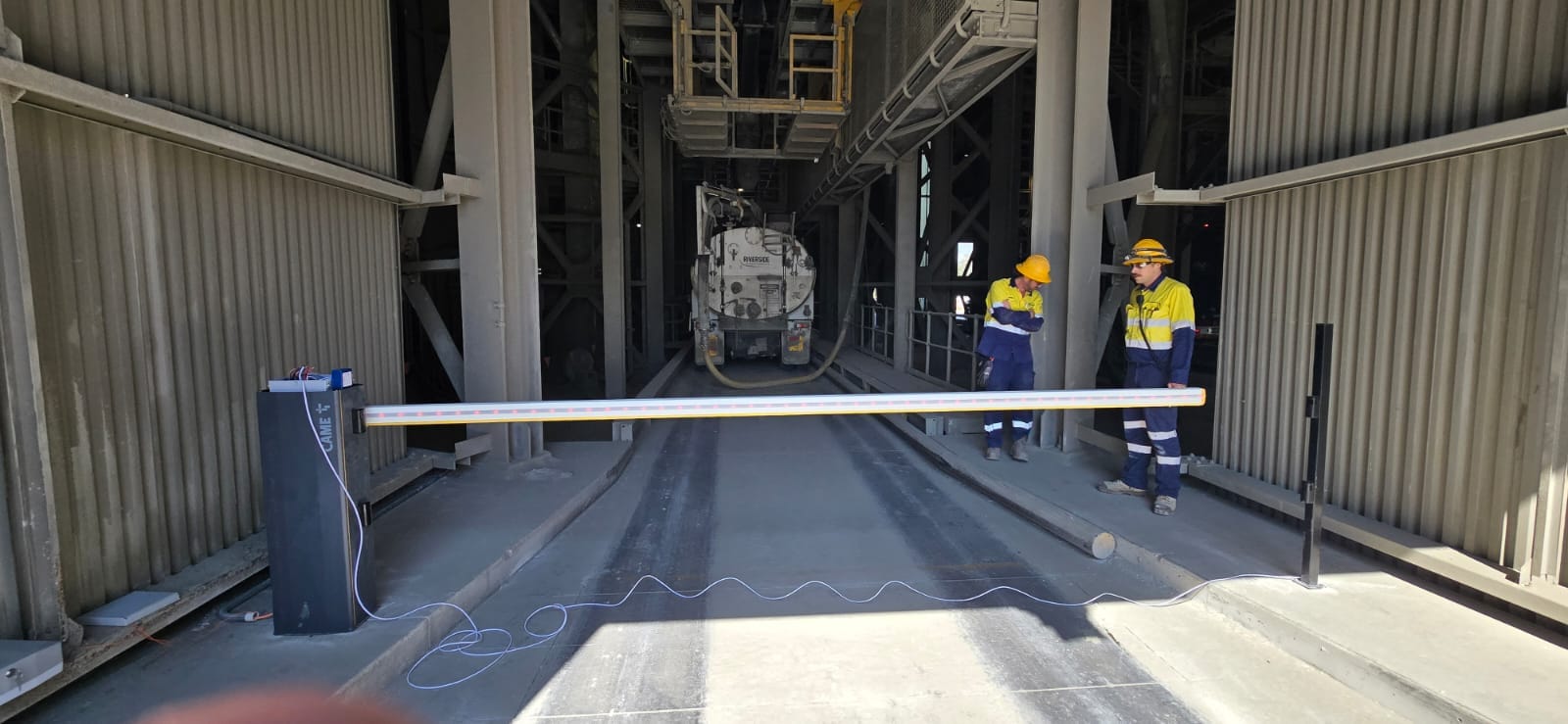 Workers testing a boom gate during an industrial service visit.