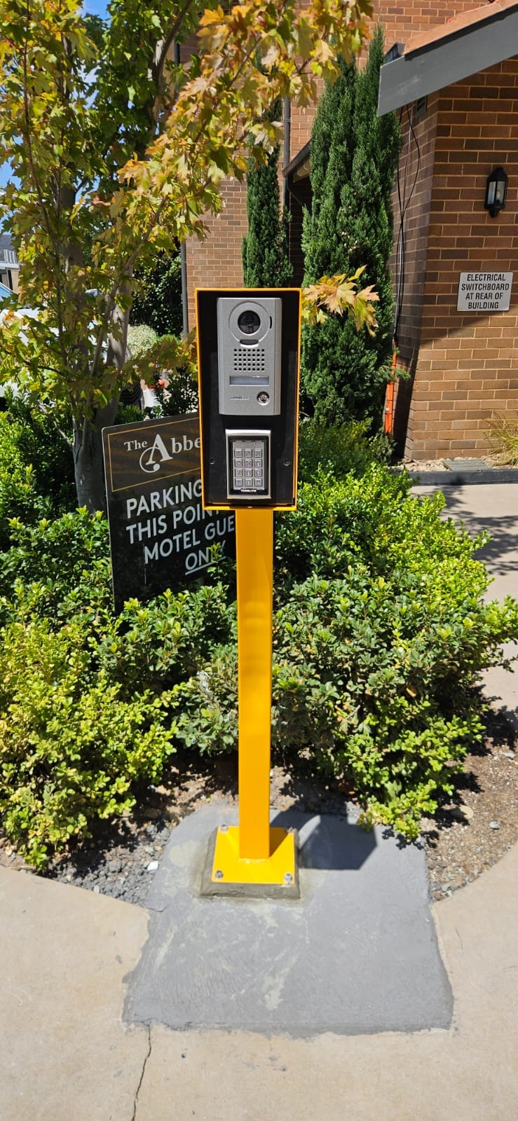 Yellow intercom keypad pedestal for car park and gate access.