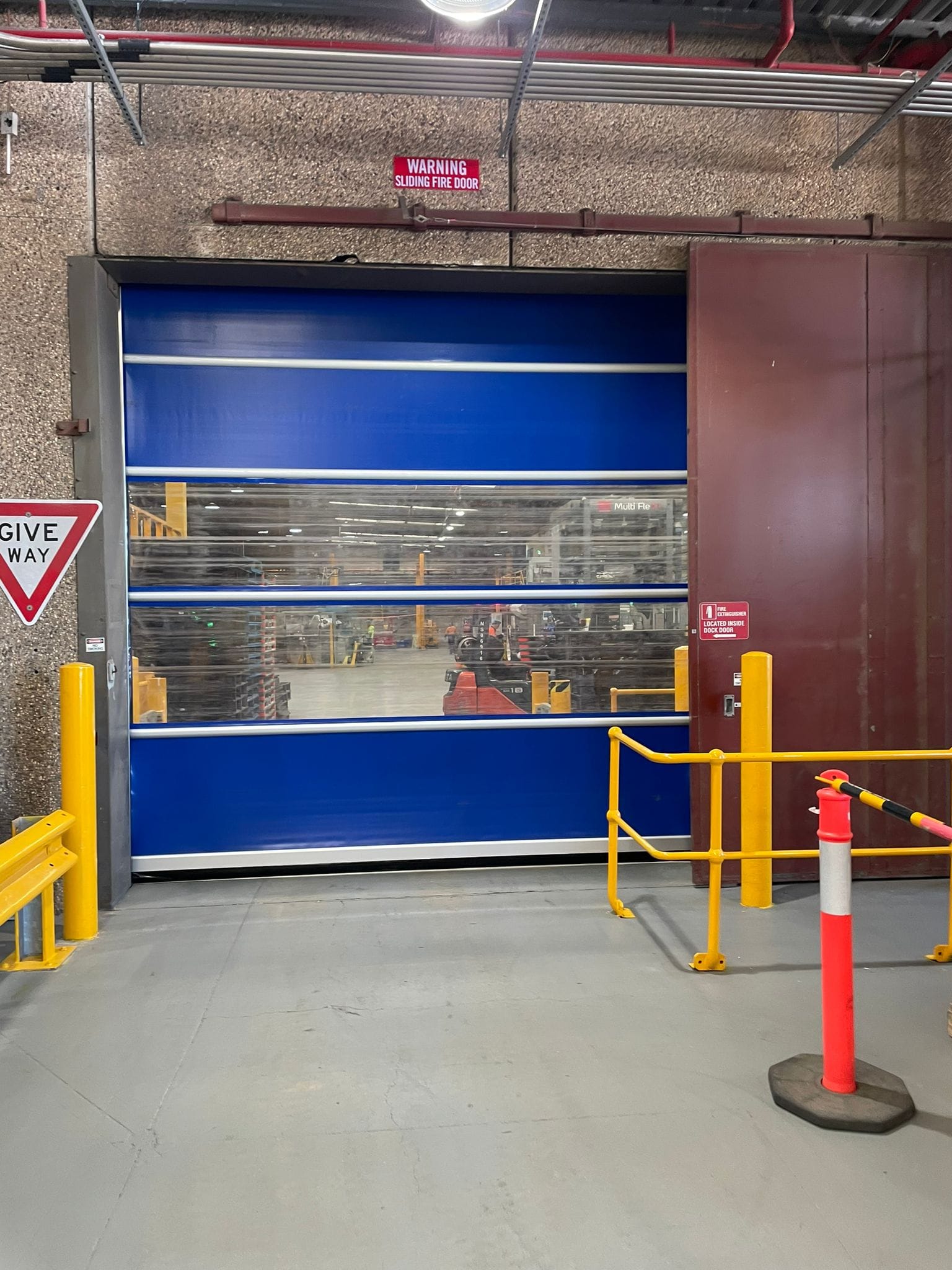Blue high-speed door with vision panels in a warehouse.