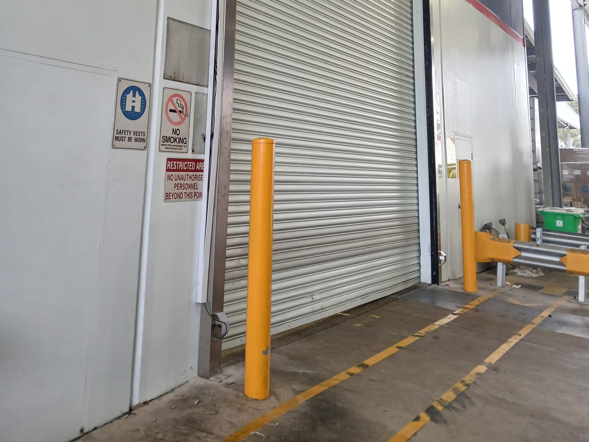 Installed bollard system protecting an industrial shutter and restricted area.