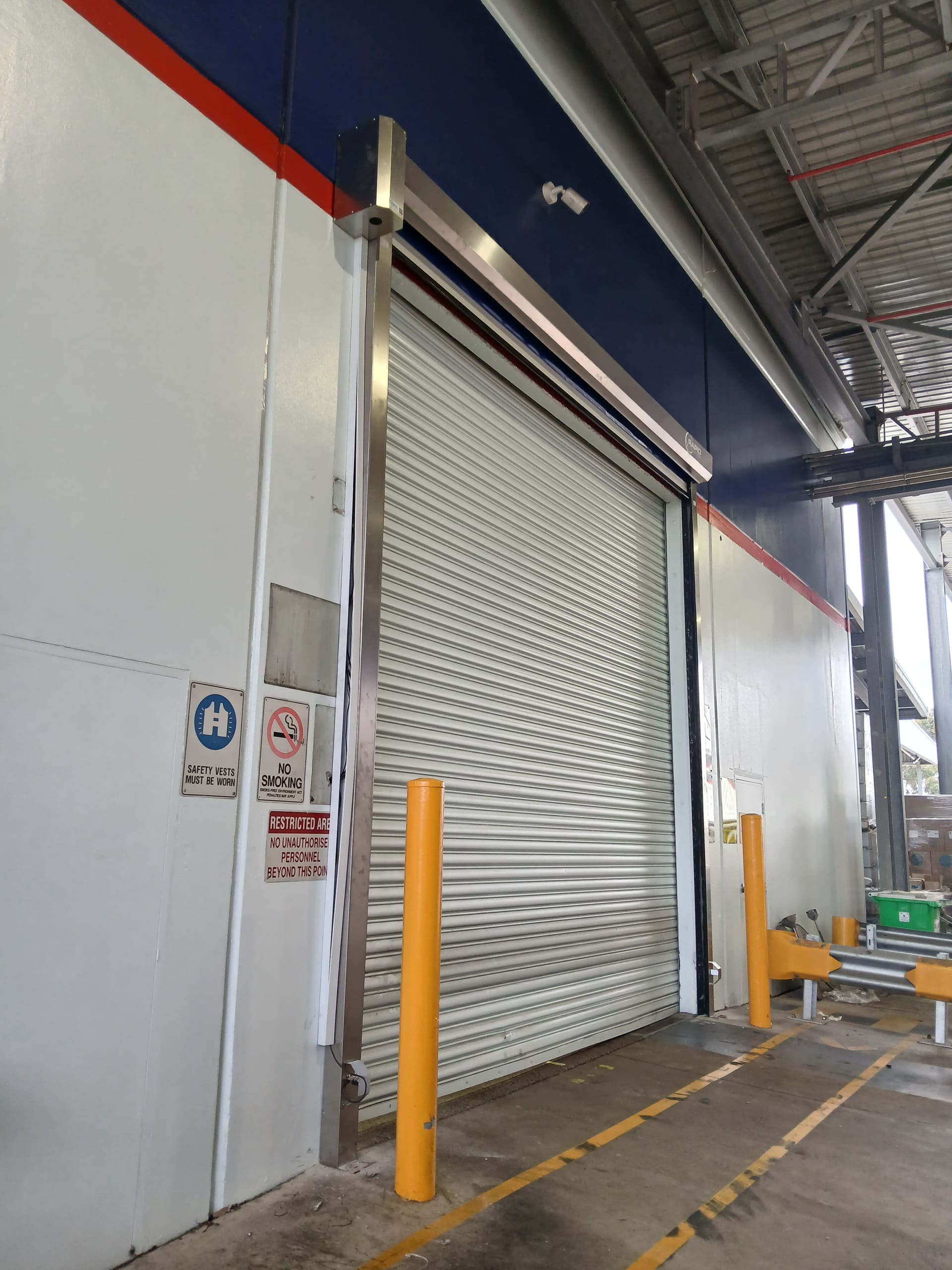 Commercial industrial door opening protected by bollards and signage.
