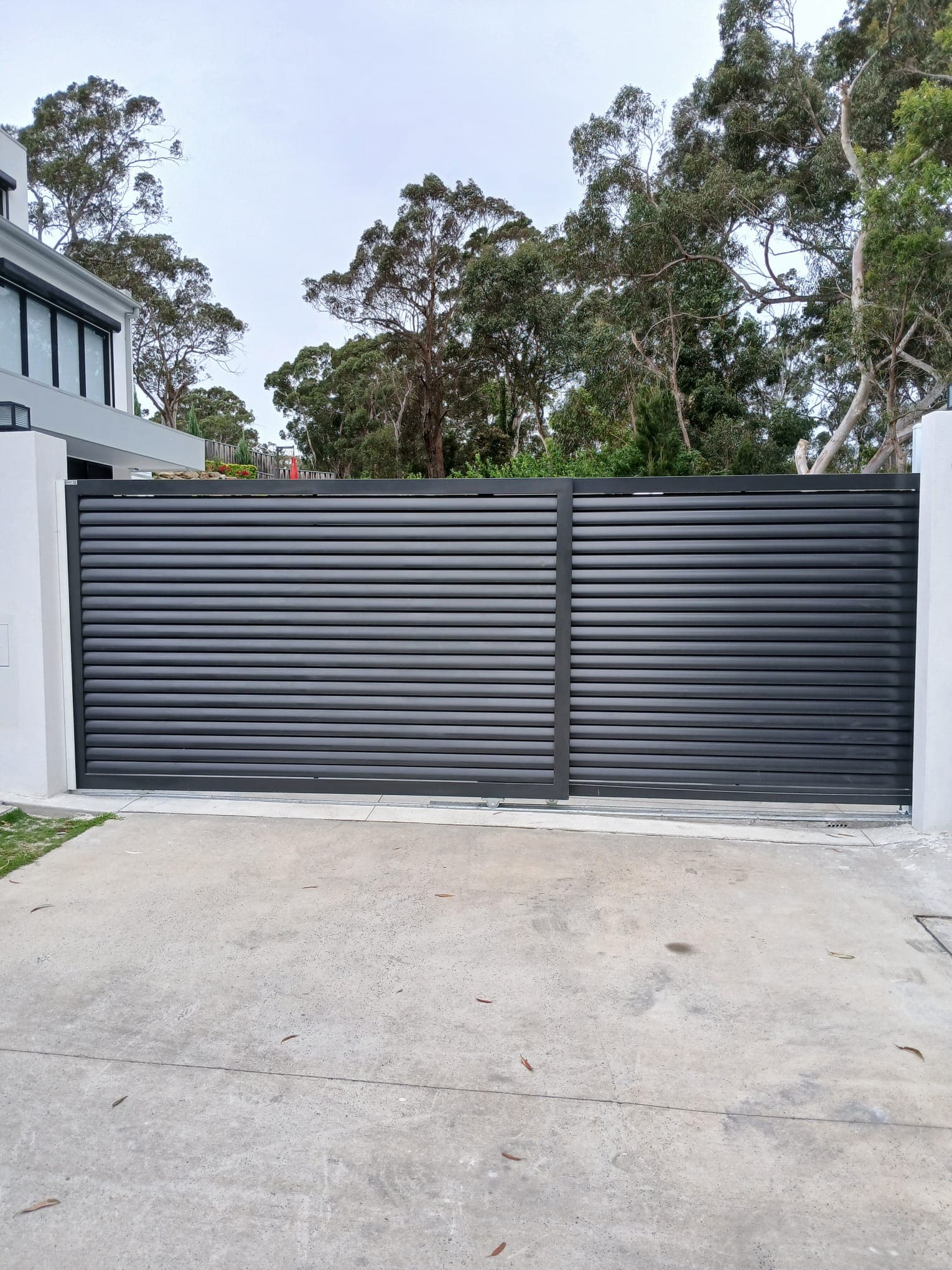 Completed charcoal automatic sliding gate across a residential driveway.