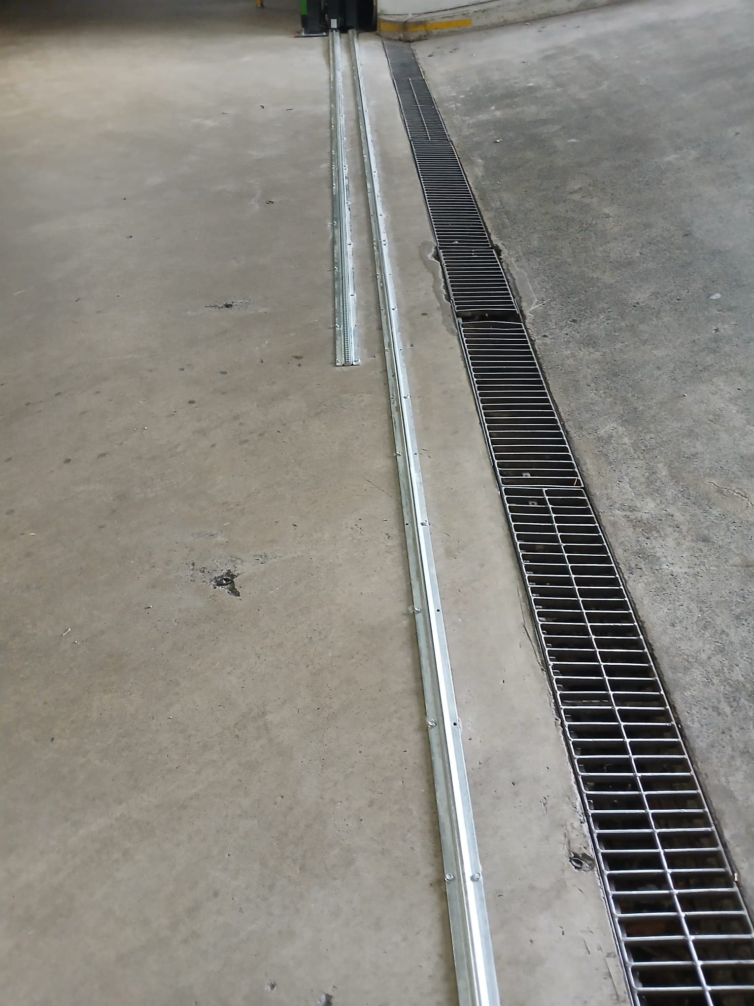 Sliding-gate ground track and drainage channel in an indoor car park