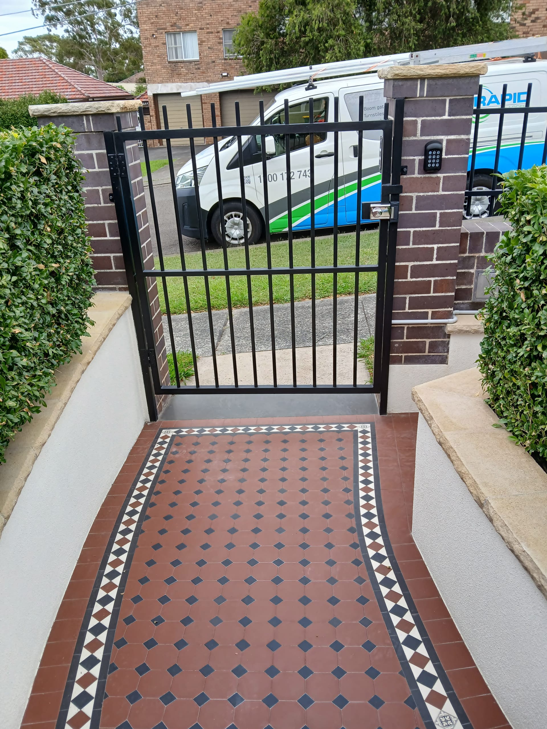 Pedestrian gate with keypad access control at a tiled entry.