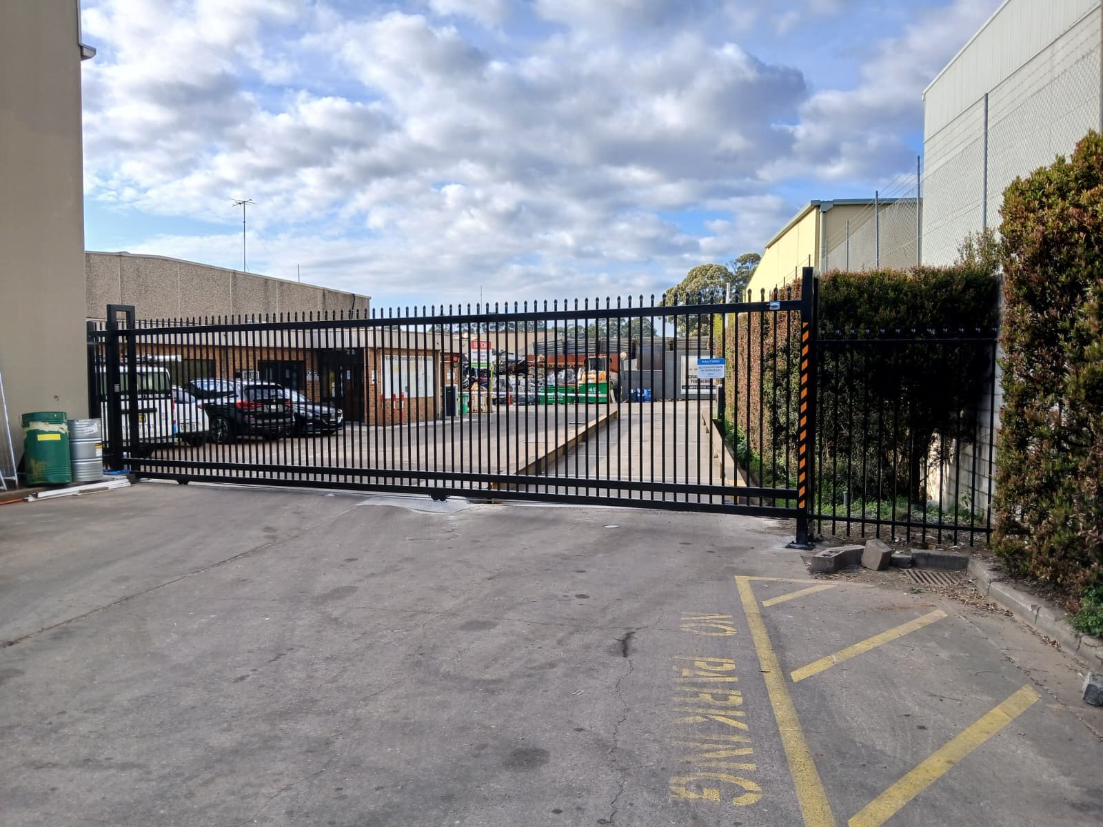 Black commercial sliding gate closed across a driveway entrance.